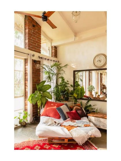 A comfortable daybed sits in a sunlit corner, surrounded by plants. We design our spaces to be lived in and loved, with plenty of room for relaxation and play.