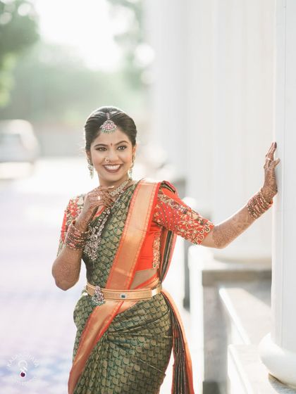 A happy bride posing against white pillars, her smile lighting up the frame.
