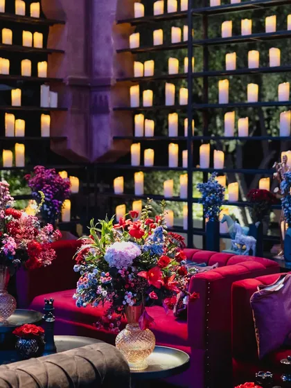 A lounge area at the Jaisalmer reception, with plush red velvet sofas set against a wall of glowing candles, creating a warm and luxurious seating nook.