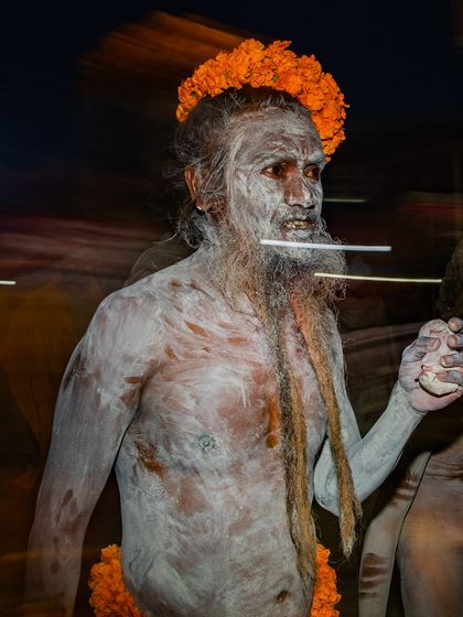 A motion-blurred image of a Naga sadhu during a procession at the Kumbh Mela. The effect captures the dynamic energy and movement of the festival.