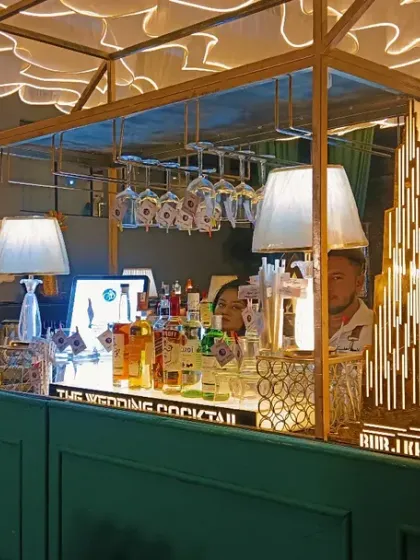 A full view of a stunning art-deco themed bar I designed for a wedding. The setup includes custom light fixtures, hanging glassware, and unique decorative pieces like the stag head.
