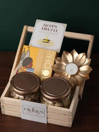 This budget-friendly wooden basket hamper feels luxurious. It contains two jars of coated nuts, Phool incense cones, and a golden flower diya, perfect for bulk corporate orders.