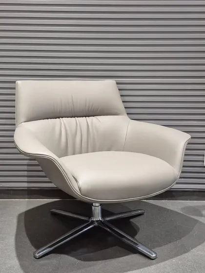 This light grey leatherette lounge chair features a swivel base and soft, gathered detailing on the backrest. It's a comfortable and sophisticated choice for a modern living room or office reception.