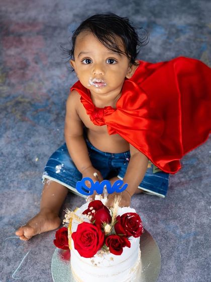 A portrait of the birthday hero. This overhead shot from the Superman cake smash captures a sweet moment amidst the fun.