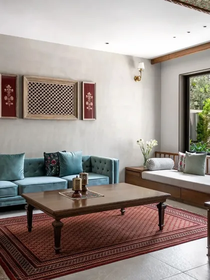The main living area is a comfortable and inviting space, with a plush sofa, a traditional Indian rug, and curated wall art.