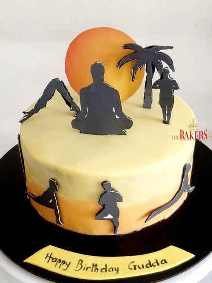 A peaceful and serene yoga-themed cake to celebrate International Yoga Day. The design features silhouettes of various yoga poses against a sunset backdrop.