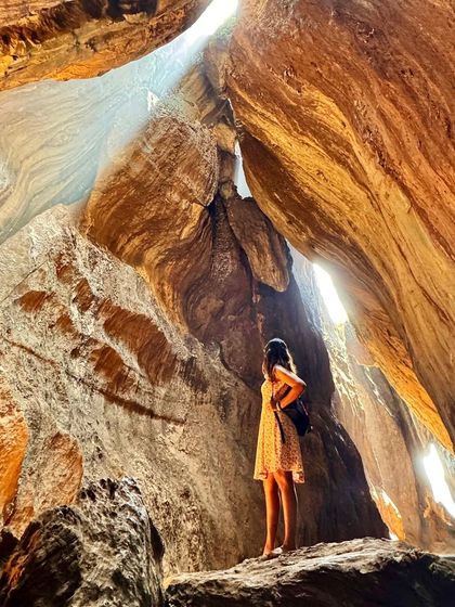 A traveler exploring the beautiful patterns inside a natural cave formation. We love finding these unique spots for you to discover.