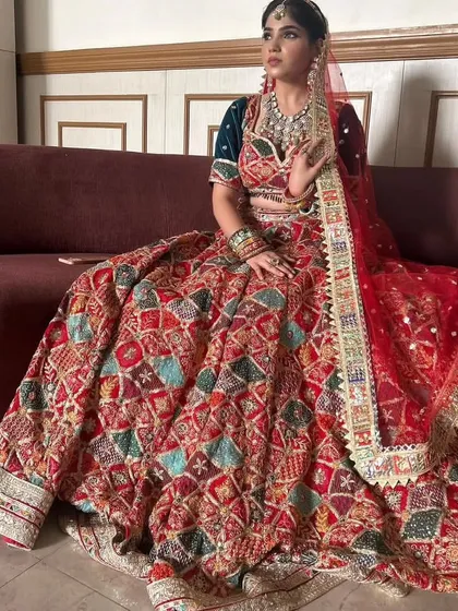 I love the rich patchwork on this red bridal lehenga. It combines different fabrics and embroidery styles, making it a unique and artistic choice for your wedding day.