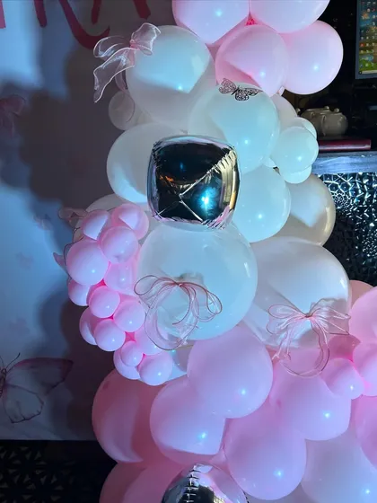 A detailed shot of the balloon work, showing the mix of pink and white balloons with silver accents and delicate ribbon bows.