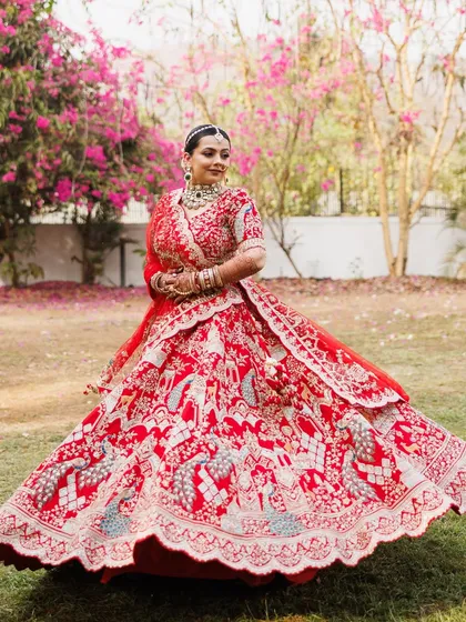 The quintessential Indian bride in a magnificent red lehenga. This full-length shot captures the grandeur and romance of a traditional wedding, a look that I have perfected for countless happy brides.