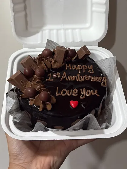 This decadent chocolate bento cake is perfect for an anniversary. It's topped with KitKat pieces, chocolate swirls, and a heartfelt message.