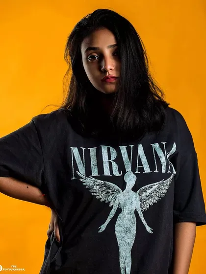 A studio portrait with a bold yellow background. The simple, clean lighting and background make the subject and her graphic tee pop.