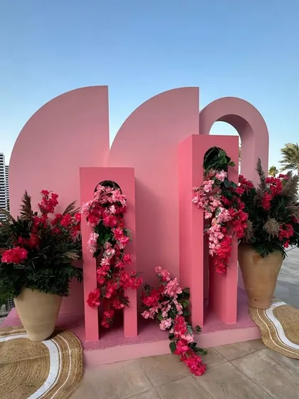 Where blooms meet geometry. This sculptural pink backdrop, adorned with flowers, served as a modern and artistic photo-op for a beach celebration in Doha. 🩷