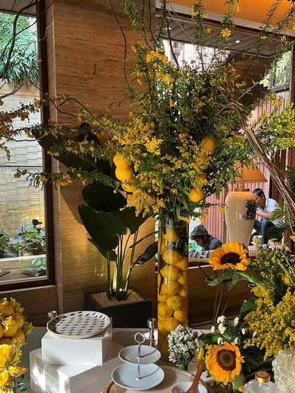 A tall vase arrangement of lemons and yellow oncidium orchids, part of a larger summer-themed event. This piece adds height and a touch of Italian-inspired elegance to the decor.