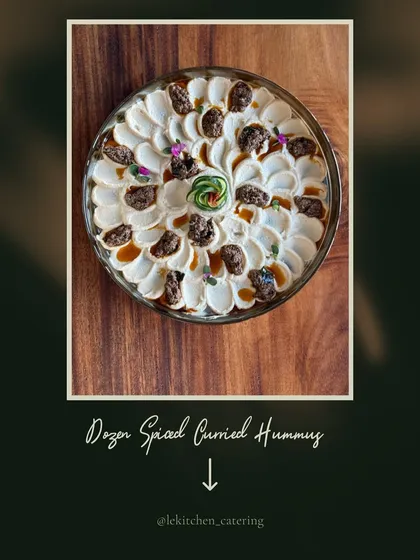 Our Dozen Spiced Curried Hummus, a unique fusion dip that brings together Middle Eastern and Indian flavors, garnished with caramelized onions and edible flowers.