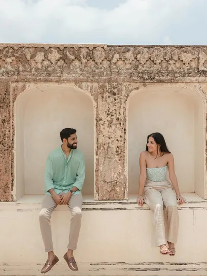 A shared glance while sitting in the alcoves of an ancient fort wall. This symmetrical composition creates a feeling of balance and connection, a signature of our architectural pre-wedding shoots.