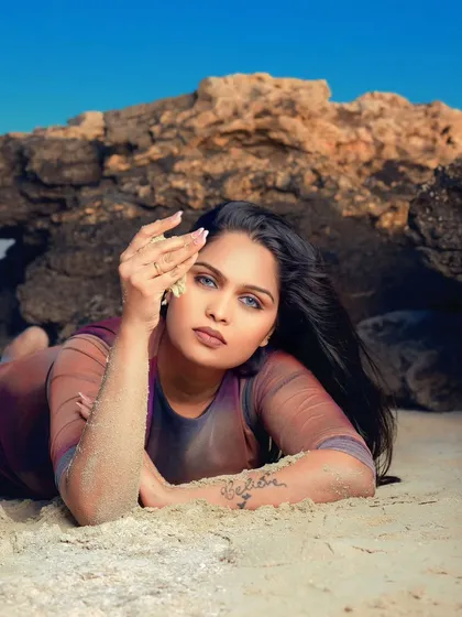 Lost in the rhythm of the waves. A beautiful beach portrait with the model lying on the sand, her striking blue eyes looking directly at the camera.