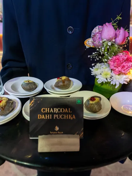 Charcoal Dahi Puchka, an innovative twist on a street food favourite. Served by our attentive staff, these bites offer a surprising and delicious experience.