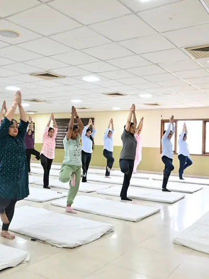 An instructor guides a class through Tree Pose at our Hoshiarpur studio. Our indoor classes provide a focused environment for students to improve their balance and concentration.