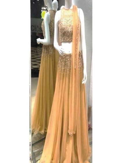 This golden lehenga, seen here on a mannequin in our store, features a fully sequined sleeveless crop top and a flowing net skirt. It's a glamorous and festive choice for any evening celebration.