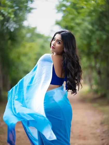 A beautiful shot of a model in a blue ombre saree, with the fabric flowing in the wind.