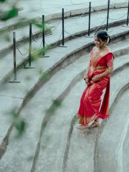 A bride in a red saree descends the curved stone steps of the amphitheater, a dramatic and unique photo opportunity.