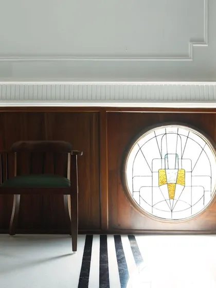 For another heritage restaurant, we restored and refreshed the original architectural details. This circular Art Deco stained-glass window became a focal point, complemented by new wood paneling and black-and-white striped marble flooring to honor the building's history.
