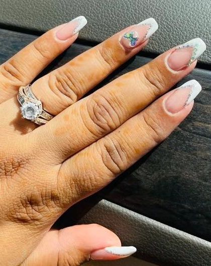 A classic white French tip on long, square-shaped nails, with a subtle butterfly charm accent for a delicate touch.