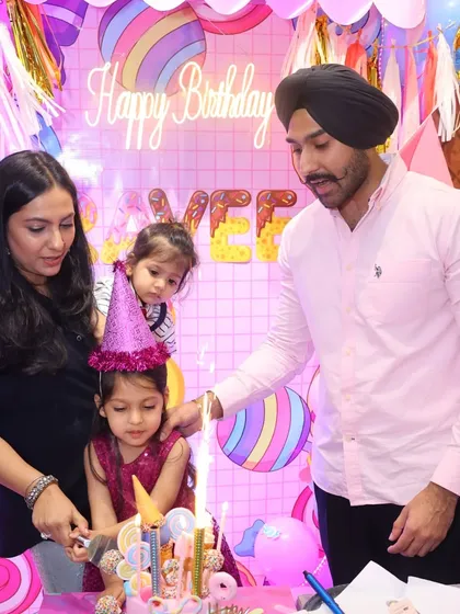 A precious moment of the birthday girl cutting her cake with her family during a sweet Candyland-themed party. These are the moments to cherish.