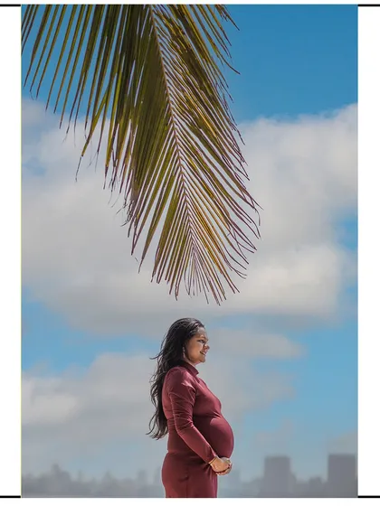A beautiful profile shot on the beach, with a palm leaf framing the mom-to-be against a blue sky.