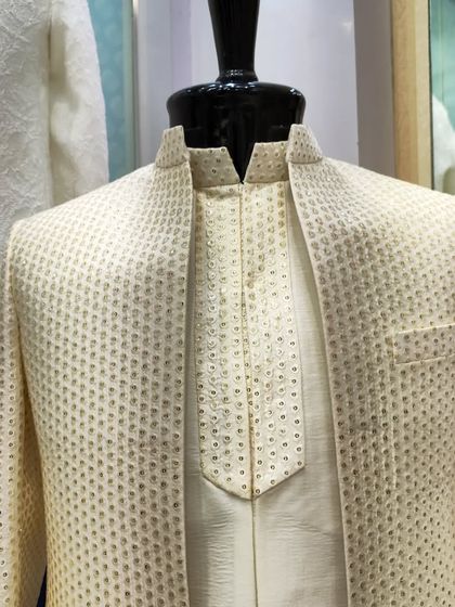 A close-up of the textured cream open sherwani-jacket, focusing on the fabric's unique weave and the matching inner kurta.