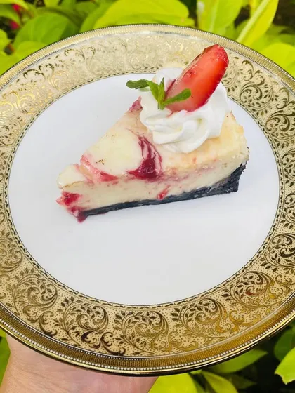 A perfect slice of our classic Strawberry Cheesecake. It's the perfect balance of creamy, tangy, and sweet, with a dollop of whipped cream and a fresh strawberry.