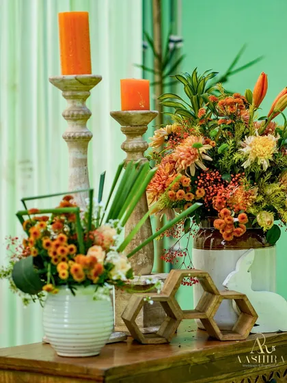 A closer look at the beautiful floral arrangement in warm orange tones, set against a soft mint green backdrop.