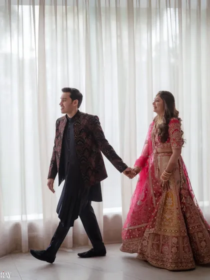 A classic walking pose, with the couple holding hands against a softly lit background. This shot feels both elegant and natural, capturing a simple moment of togetherness.
