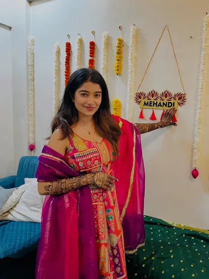 A playful pose from Shrutika, holding up her mehendi-adorned hand to the "Mehandi" sign.