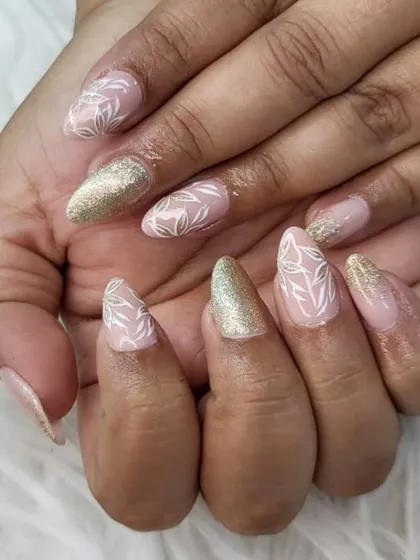 This elegant almond-shaped set combines a soft nude base with hand-painted white leaf patterns and accent nails in a brilliant gold glitter. It’s a popular choice for brides and bridesmaids alike.