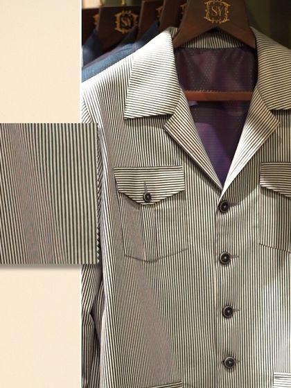 A detailed view of a striped shacket with a fabric swatch. The image highlights the clean lines of the pockets and the quality of the pinstripe material.