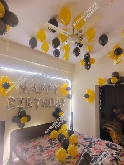 A bedroom decorated with yellow and black balloons for a birthday.