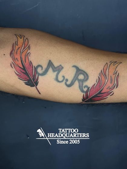 A great example of a creative cover-up. We used two vibrant, fire-themed feathers to beautifully transform the original "M.R." initial tattoo.