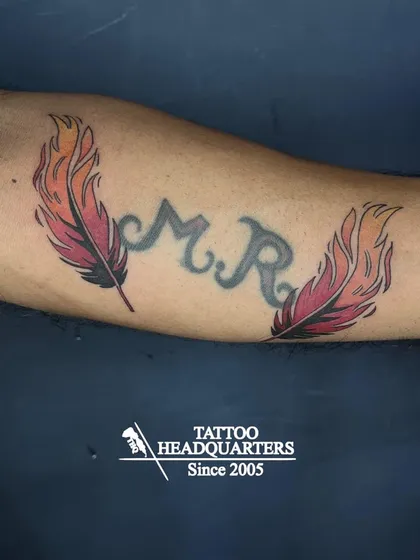 A great example of a creative cover-up. We used two vibrant, fire-themed feathers to beautifully transform the original "M.R." initial tattoo.