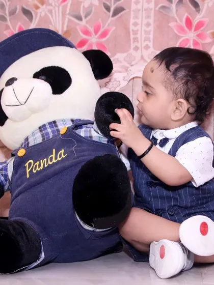 A candid photo of a baby boy playing with his panda teddy bear at home. We offer at-home sessions to capture children in their most comfortable environment.