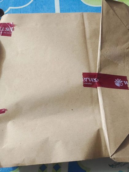 A customer's view of their premium thali order, neatly packed in a brown paper bag and sealed. This is how your comforting meal arrives at your doorstep.