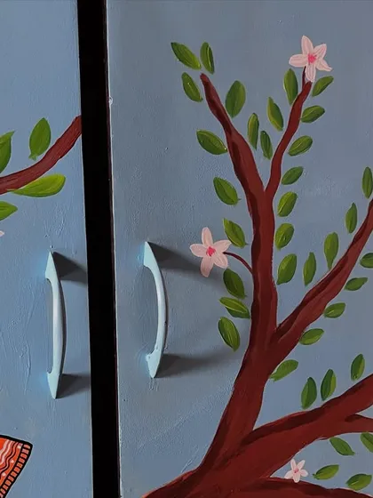 This image focuses on how the artwork seamlessly integrates with the furniture's hardware. The painted branches appear to grow naturally around the handles, showing a thoughtful approach to the upcycled furniture design.
