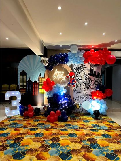 A modern and graphic Spiderman theme for a 3rd birthday. This setup uses stylized backdrops of a city skyline and comic book art, combined with balloons and a marquee number.