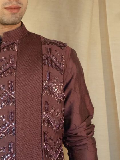 This exquisite brown silk kurta is a masterpiece adorned with intricate embellishments, including sequins and pintucks.