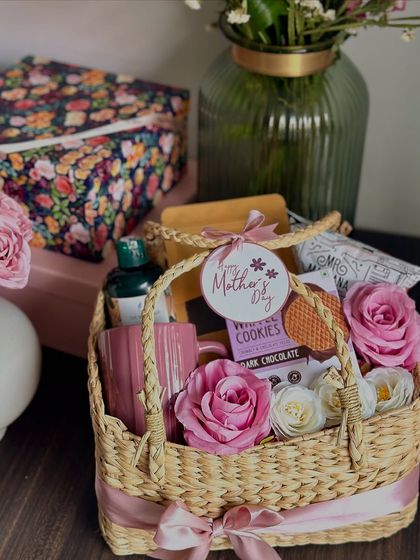 A lovely Mother's Day basket filled with Assam tea, a coffee mug, a Body Shop shower gel, and other treats, adorned with beautiful pink roses.