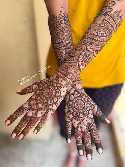 A full and rich engagement mehendi with mandala patterns on the palm and intricate work up to the mid-arm.