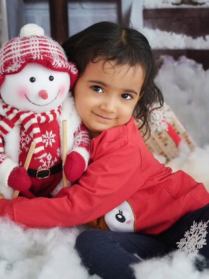 A little girl hugging her snowman friend. My studio is filled with festive props for kids to interact with, making the session a fun experience for them.