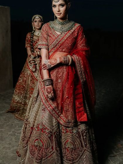 A dramatic, full-length shot from a campaign, showing the flow and grandeur of the bridal lehengas.