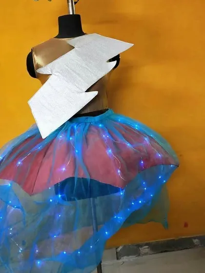 A student's creative project displayed on a mannequin. This avant-garde piece includes a skirt made of blue net with integrated fairy lights, showing how students experiment with technology and non-traditional elements in fashion.